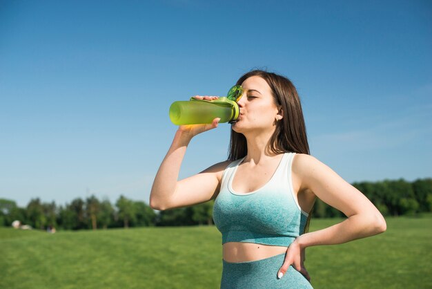 Athletische Frau, die isotonisches Wasser trinkt