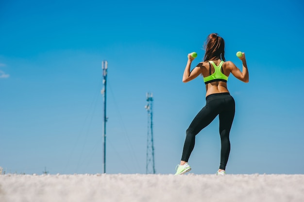 athletische Frau, die Muskeln mit Hanteln aufpumpt