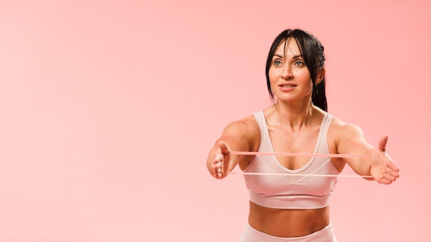 Foto athletische frau, die widerstandband mit kopienraum ausdehnt