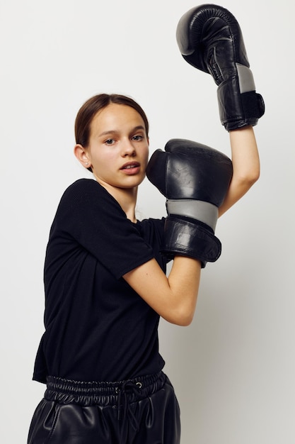 Athletische Frau in schwarzen Sportuniform-Boxhandschuhen, die isolierten Hintergrund posieren