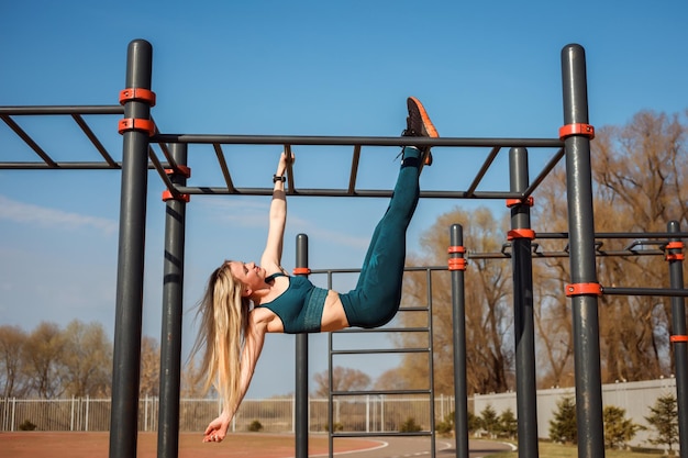 Athletische Frau trainiert im Frühling im Freien und hat Spaß an der horizontalen Stange