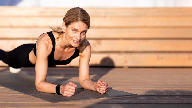 Athletische Frauen mittleren Alters trainieren im Freien und machen Plank-Übungen