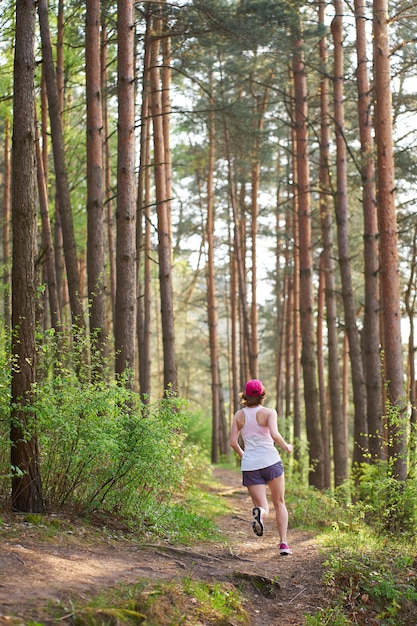 Athletische junge Frau in den rosa Turnschuhen lassen im Frühjahr Wald laufen