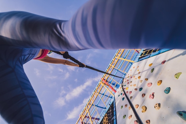 Athletische junge Frau trainiert und klettert im Trainingslager am Kunstfelsen