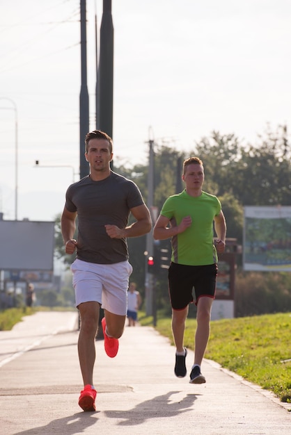 athletische junge männer laufen gerne, während die sonne über der stadt aufgeht
