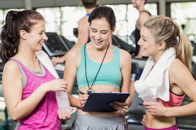 Athletische lächelnde Frauen, die über Leistung in der Turnhalle sich besprechen