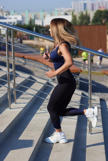 Athletische schlanke Frau an einem sonnigen Tag läuft entlang der Böschung oder des Parks