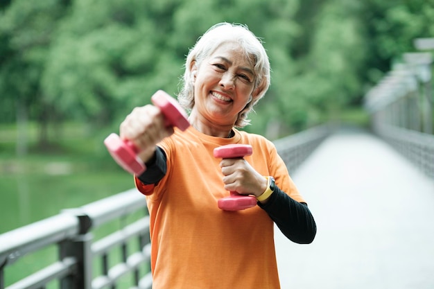 Athletische Seniorin hebt Hanteln, während sie Fitness macht