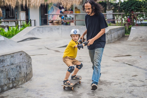 Athletischer Junge lernt Skateboard mit einem Trainer in einem Skatepark Kindererziehungssport