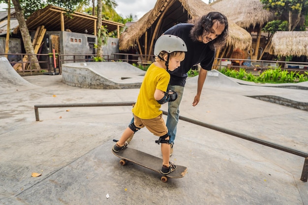 Athletischer Junge lernt Skateboard mit einem Trainer in einem Skatepark Kindererziehungssport