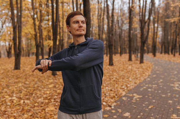 Athletischer männlicher Jogger, der sich beim Fitnesstraining im Park dehnt und aufwärmt
