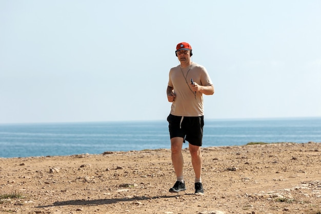 Athletischer Mann, der an sonnigen Sommertagen im Park mit Kopfhörern läuft Gesunder Lebensstil Aktive erwachsene Männer joggen