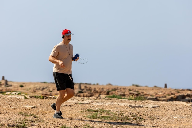 Athletischer Mann, der an sonnigen Sommertagen im Park mit Kopfhörern läuft Gesunder Lebensstil Aktive erwachsene Männer joggen
