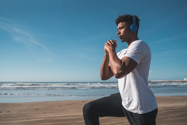 Athletischer Mann, der Übung am Strand tut.