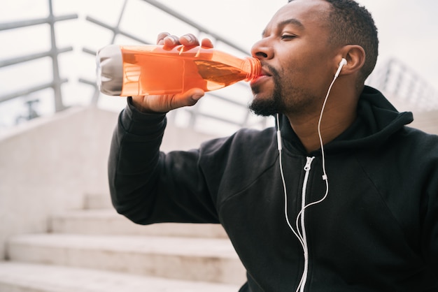 Athletischer Mann, der etwas nach dem Training trinkt