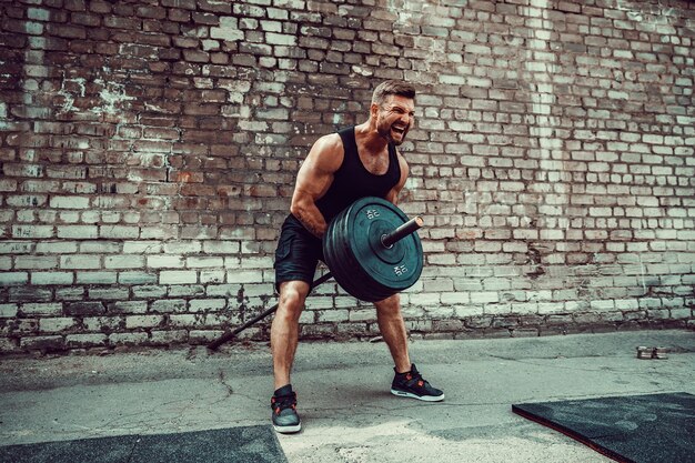 Athletischer Mann, der mit einem Barbell ausarbeitet. Kraft und Motivation. Übung für die Rückenmuskulatur