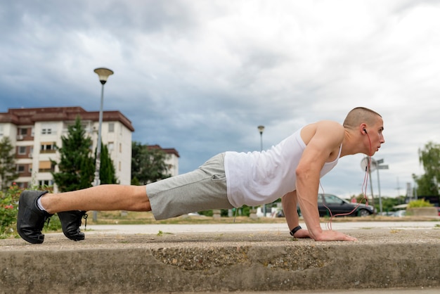 Athletischer Mann, der Push-up auf einer Straße bei Sonnenuntergang tut.