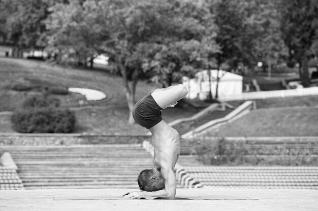 Foto athletischer mann, der yoga-asanas im park macht