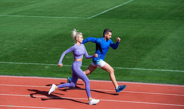 Athletischer Mann und Frau von Sprintern laufen auf der Laufstrecke im Stadion