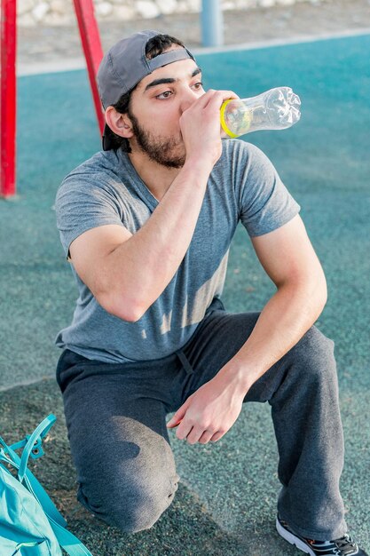 Athletischer Sportler trinkt Wasser aus einer Flasche