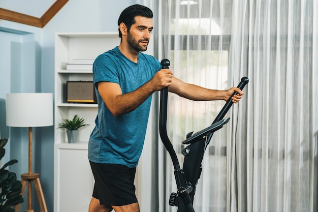 Athletischer und sportlicher Mann läuft auf einer elliptischen Laufmaschine im Haus von Gaiety