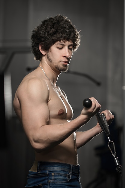 Athletisches muskulöses Manntrainingsbizeps in der Turnhalle