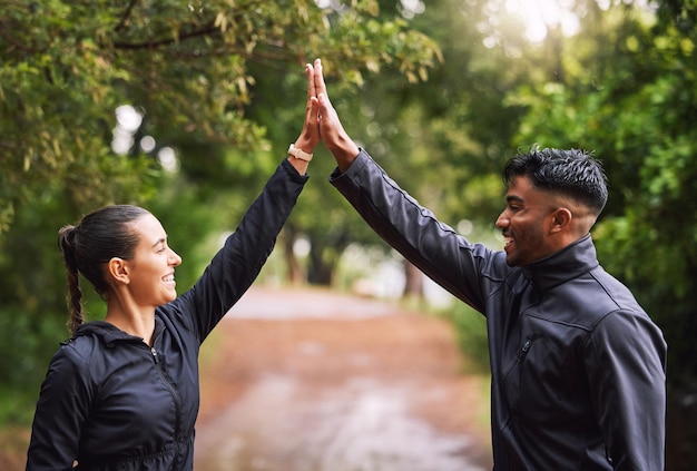 Athletisches Paar High Five beim Trainieren in einem Park oder Wald Feiern und Gewinnen vor einem Lauf Passen Sie Freund und Freundin an, während Sie fit und gesund bleiben Spaßliebhaber, die aktiv sind