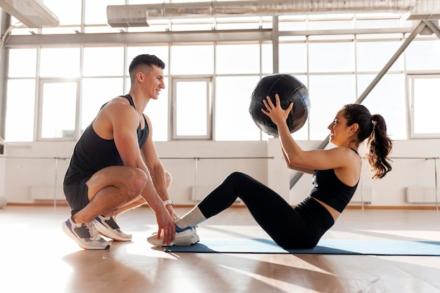 Athletisches Paar in Sportbekleidung trainiert mit Ball am Morgen Fitness-Mädchen trainiert auf der Presse