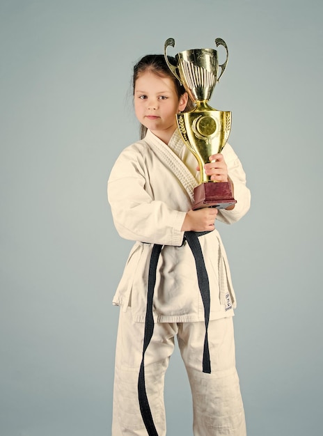 Atividade de energia nocaute para crianças menina pequena com prática de artes marciais da Copa do campeão Kung Fu feliz sucesso esportivo na infância em um vencedor de combate único menina em roupas esportivas gi Simplesmente o melhor