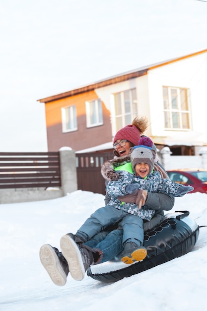 Atividade de inverno para mãe e filho, deslize da colina de neve