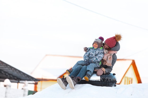 Atividade de inverno para mãe e filho, deslize da colina de neve