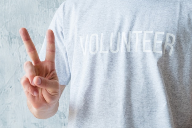 Atividade de voluntariado. conceito de estilo de vida moderno. homem de camiseta mostrando o sinal v.