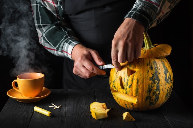 Atividade divertida para a família - abóbora esculpida em jack-o-lantern para o dia das bruxas close-up. Paerson segurando uma faca