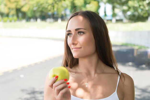 Atividade e energia de verão. esporte e saúde. mulher segura maçã verde. garota fazendo dieta ensolarado ao ar livre. frutas e vitaminas.