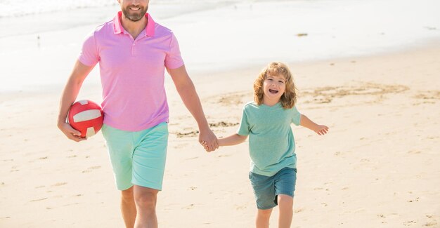 Atividade esportiva de férias em família recortada pai e filho andando com bola na praia