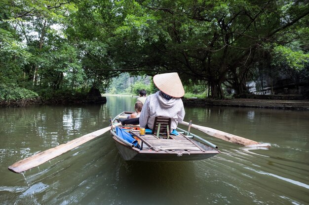 Atividade rio abaixo em barco com vietnamitas usando remo a pé no rio Ngo Dong, Ninh Binh, Baía de Halong em terra