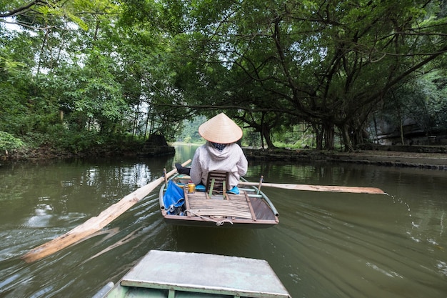 Atividade rio abaixo em barco com vietnamitas usando remo a pé no rio Ngo Dong, Ninh Binh, Baía de Halong em terra