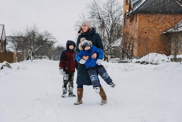 Atividades ao ar livre em família para férias de inverno felizes, feliz mãe e dois filhos jogando bolas de neve no