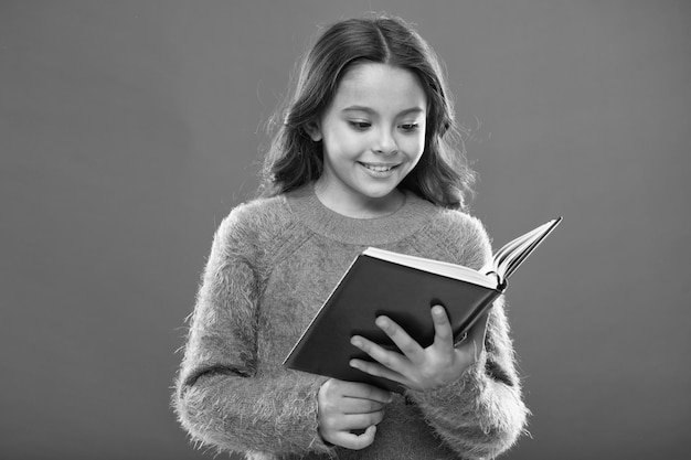 Atividades de leitura para crianças menina segura livro lê história sobre fundo laranja criança gosta de ler livro conceito de loja de livros maravilhosos livros infantis gratuitos disponíveis para ler literatura infantil