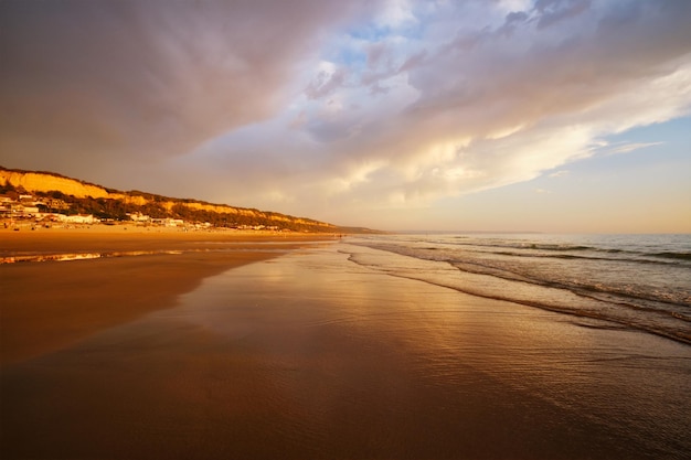 Atlantischer Ozeansonnenuntergang mit wogenden Wellen am Strand von Fonte da Telha in Portugal