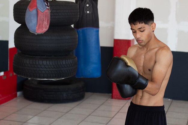 Atleta adolescente asiático delgado poniéndose guantes de boxeo