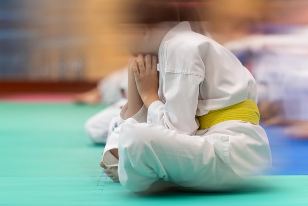 Foto atleta adolescente en un kimano blanco con un cinturón amarillo en el tatami antes de la pelea el concepto de desenfoque de movimiento visual y poca profundidad de campo