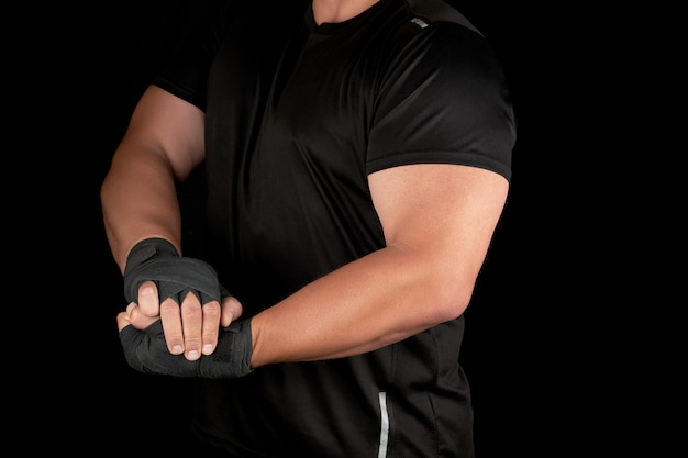 Atleta adulto en uniforme negro está de pie en un estante con músculos tensos