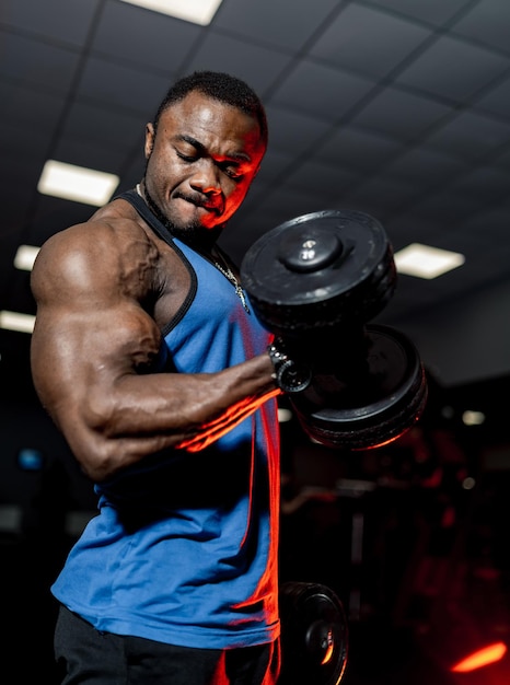 Atleta africano no ginásio Fisiculturista muscular malhando no ginásio em uma máquina de cabo