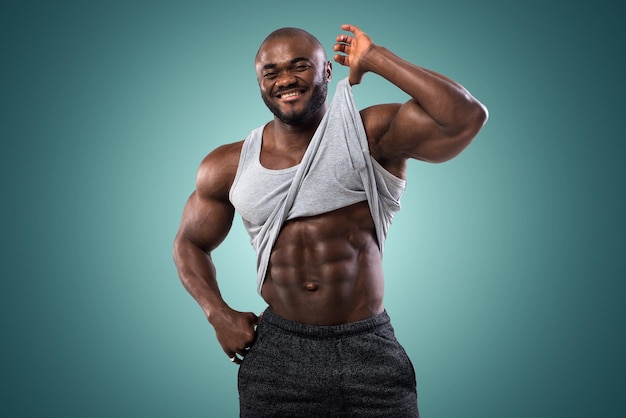 Atleta afro-americana posando no estúdio. Mostra os músculos abdominais sob a camisa