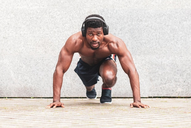 El atleta afroamericano está enfocado en comenzar. El corredor atlético está listo para correr. El chico está entrenando.