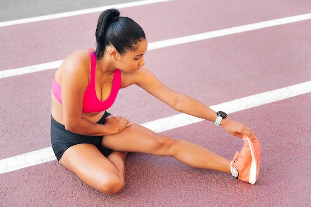 Atleta alongando sentado na pista de atletismo