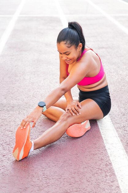 Atleta alongando sentado na pista de atletismo