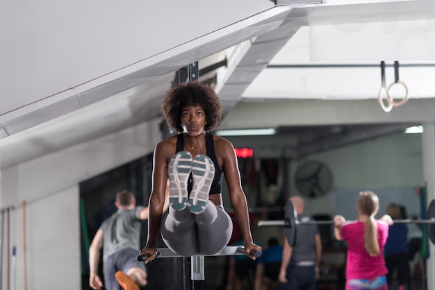 atleta americano africano mulher treino de braços em mergulhos barras paralelas horizontais Treino de exercício tríceps e bíceps fazendo flexões