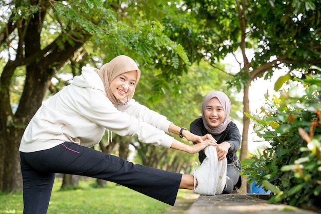 Atleta amiga muçulmana esticando a perna ao ar livre juntas